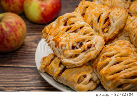 Pile of apple puffs on a plate on a brown background Pile of apple puffs on a plate on a brown background 82782304