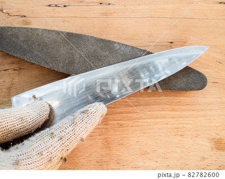 gloved hand sharpens a kitchen knife closeup gloved hand sharpens a kitchen knife closeup 82782600