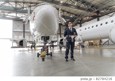 Professional pilot holding a cap in his hands and looking to the side Professional pilot holding a cap in his hands and looking to the side 82784216