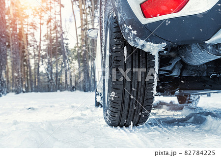 Close-up detail view of car wheel with unsafe summer tread tire during driving through slippery snow road at winter season. Danger traffic accident collision risk. Seasonal tyre switch concept 82784225