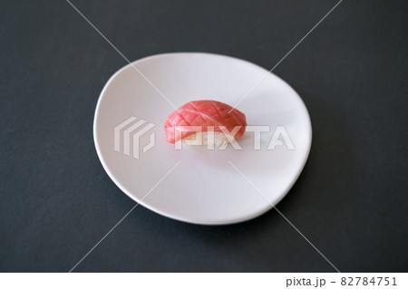 Sushi Nigiri with raw tuna served on white plate. One sushi piece on the black background. Japanese traditional food.  82784751