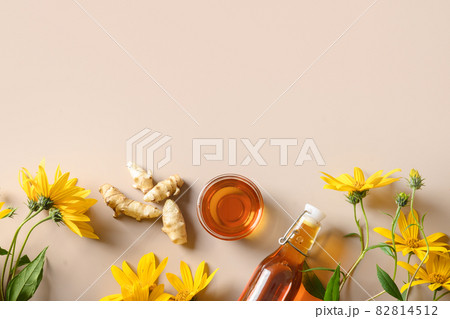 Jerusalem artichoke syrup in bottle, flowers and root. 82814512