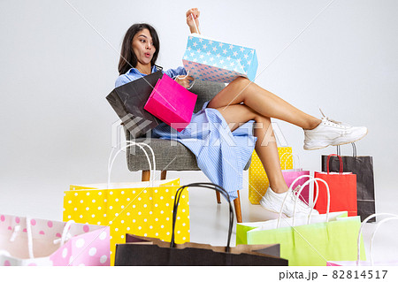 Close-up surprised young girl after shopping at black friday sales. Model with lots of bags, colorful bright packages isolated over white studio background. 82814517