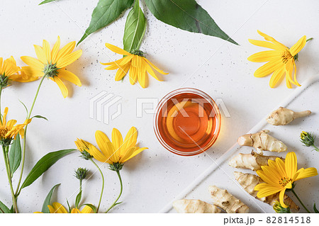 Jerusalem artichoke syrup in bowl, flowers and root. 82814518