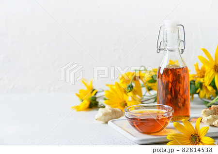 Jerusalem artichoke syrup in bottle, flowers and root. 82814538