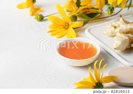 Jerusalem artichoke syrup in bowl, flowers and root. Jerusalem artichoke syrup in bowl, flowers and root. 82816015