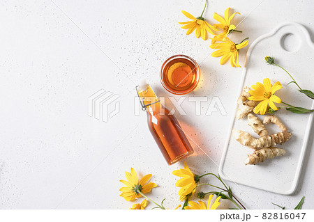 Jerusalem artichoke syrup in bowl, flowers and root. 82816047