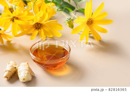 Jerusalem artichoke syrup in bowl, flowers and root. 82816365