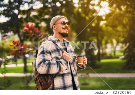 Smiling happy face of stylish man walk around park outdoor with coffee to go while having relax time 82820566
