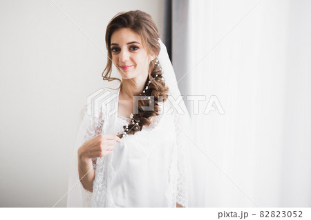 Beautiful bride wearing fashion wedding dress with feathers with luxury delight make-up and hairstyle, studio indoor photo shoot Beautiful bride wearing fashion wedding dress with feathers with luxury delight make-up and hairstyle, studio indoor photo shoot 82823052