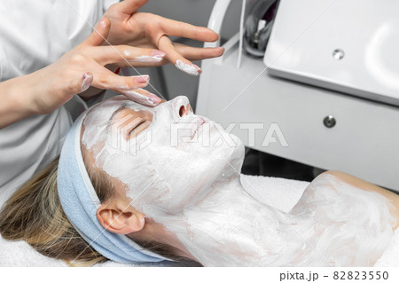 Close-up beautician doctor hand making anti-age procedure, mask and peeling for young attractive female client at beauty clinic. Cosmetologist specialist doing skincare treatment .Health care therapy Close-up beautician doctor hand making anti-age procedure, mask and peeling for young attractive female client at beauty clinic. Cosmetologist specialist doing skincare treatment .Health care therapy 82823550