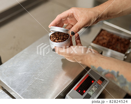 Male hands holding metal container with coffee beans 82824524