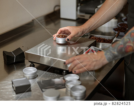 Male worker weighing coffee beans on scales 82824525