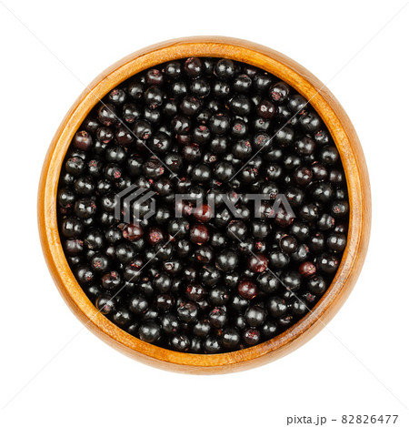 Fresh elderberries in a wooden bowl. Ripe Sambucus berries, commonly called elder or elderberry. Raw berries are poisonous while cooked berries of most species are edible and are used for wine or jam. 82826477