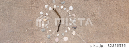 Sundial is lined with stones on sand of sea beach closeup background 82826536