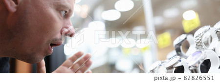 Surprised man looking at glass display case with expensive watch 82826551