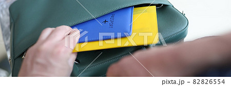 Man putting plane tickets and passport in bag closeup 82826554