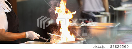 Chef in rubber gloves is cooking on fire closeup Chef in rubber gloves is cooking on fire closeup 82826569
