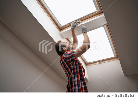 Young caucasian worker screwing skylight window handle Young caucasian worker screwing skylight window handle 82828562