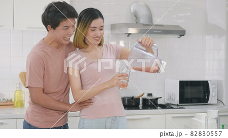 family couple husband and wife enjoying drinking fresh apple smoothie juice in kitchen family couple husband and wife enjoying drinking fresh apple smoothie juice in kitchen 82830557