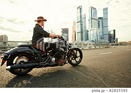 young man riding big bike ,motorcycle on city road against urban and town building scene. Motion blur 82835595