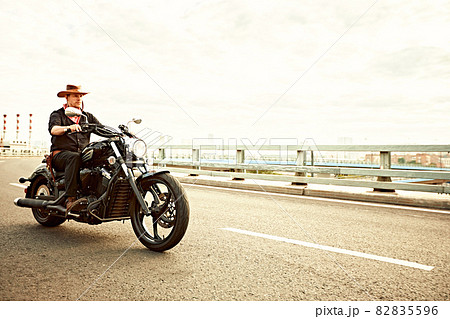 young man riding big bike ,motorcycle on city road against urban and town building scene. Motion blur 82835596