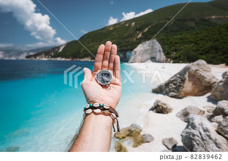Hand holding a compass on the beach in background 82839462