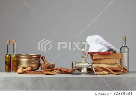 Chef's hat, vintage cookbooks, and old kitchen utensils on the kitchen table. 82839631