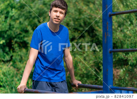 teenage boy exercising outdoors, sports ground in the yard, he does push-ups at the bars, healthy lifestyle teenage boy exercising outdoors, sports ground in the yard, he does push-ups at the bars, healthy lifestyle 82841097