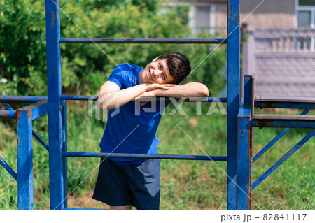 teenage boy exercising outdoors, sports ground in the yard, he posing at the horizontal bar, healthy lifestyle teenage boy exercising outdoors, sports ground in the yard, he posing at the horizontal bar, healthy lifestyle 82841117