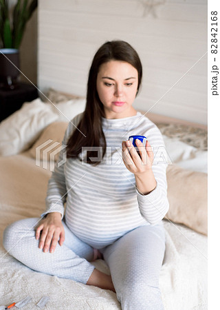 A pregnant woman checks her blood sugar using a blood glucose meter. A pregnant woman checks her blood sugar using a blood glucose meter. 82842168