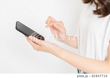 スマホを操作するTシャツを着た若い女性 82847719