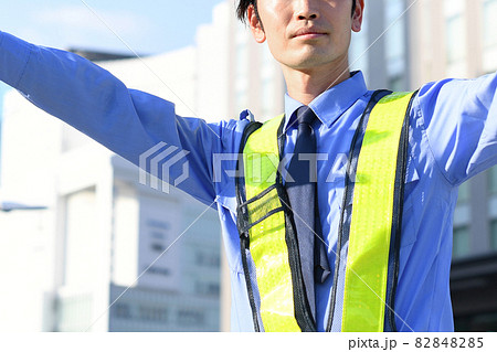 誘導棒を持つ交通誘導をするガードマンの男性 82848285