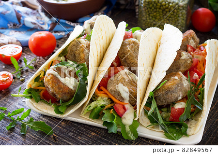 Delicious fresh homemade tortilla wrap with falafel and fresh salad on the table. Vegan tacos. Vegetarian healthy food. 82849567
