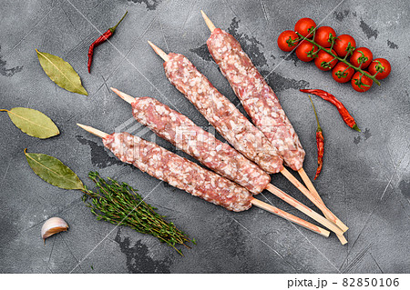 Raw beef and lamb meat kebabs sausages, with grill ingredients, on gray stone table background, top view flat lay 82850106