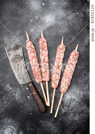 Raw kofta meat kebabs sausages, on black dark stone table background, top view flat lay 82850120