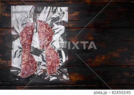 Beef patties in a vacuum packing set, on old dark wooden table background, top view flat lay, with copy space for text Beef patties in a vacuum packing set, on old dark wooden table background, top view flat lay, with copy space for text 82850240