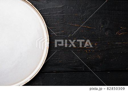 White rustic ceramic plate with copy space for text or food with copy space for text or food, top view flat lay , on black wooden table background 82850309