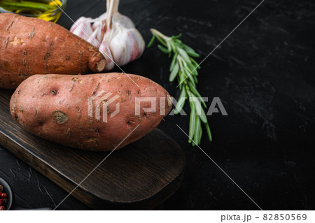 Sweet potato or batat with herbs and spices on black background with space for text Sweet potato or batat with herbs and spices on black background with space for text 82850569