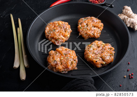 Raw fish patties with salmon and lemongrass, on black textured background 82850573