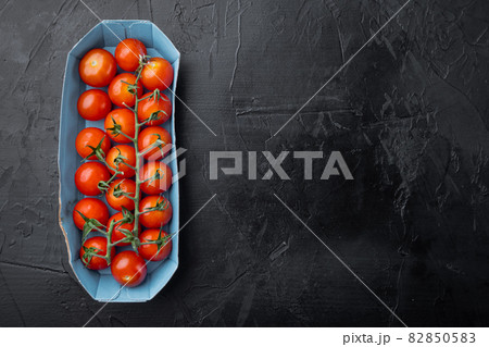 Red ripe cherry tomatoe, on black background with copy space for text 82850583