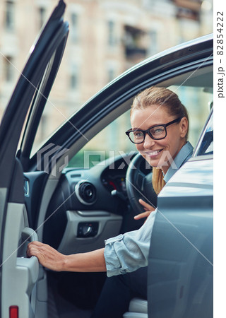 Great day. Beautiful and happy middle aged business woman in classic wear getting out of her modern car, she is arrived at work in the morning Great day. Beautiful and happy middle aged business woman in classic wear getting out of her modern car, she is arrived at work in the morning 82854222