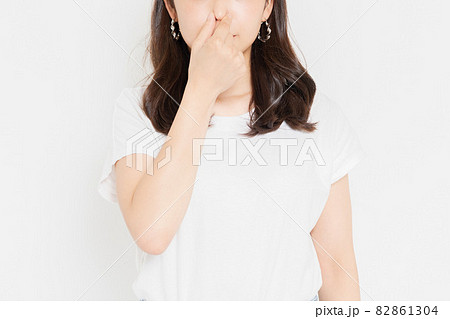 鼻をつまむTシャツを着た若い女性 82861304