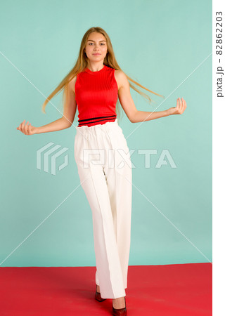 Fashion photo of a beautiful elegant young woman in a pretty red tank top, white pants 82862203