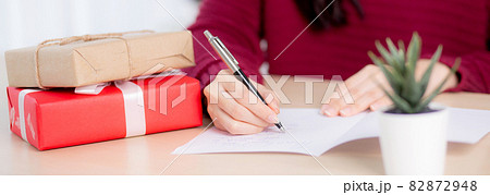 Closeup hand of young asian woman writing postcard in Christmas day at home, eve and celebrate. 82872948
