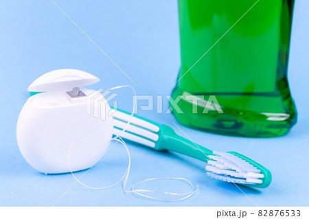 Tooth care and oral hygiene products. Dental floss, toothbrush and mouthwash on blue background Tooth care and oral hygiene products. Dental floss, toothbrush and mouthwash on blue background 82876533