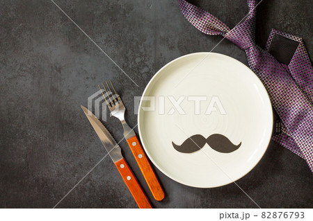 Happy fathers day concept. Table setting - plate, tie, cutlery and napkin on grey stone table. Top view flat lay background with copy space. Happy fathers day concept. Table setting - plate, tie, cutlery and napkin on grey stone table. Top view flat lay background with copy space. 82876793