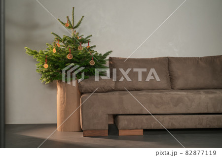 Small christmas tree with natural decorations indoor near couch 82877119