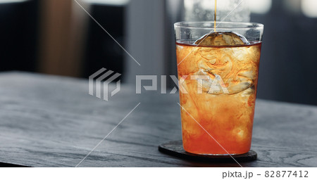 pour tonic water over clear ice ball in tumbler glass on black oak table pour tonic water over clear ice ball in tumbler glass on black oak table 82877412