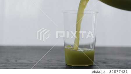 pour green matcha drink in tumbler glass on black oak table with copy space 82877421